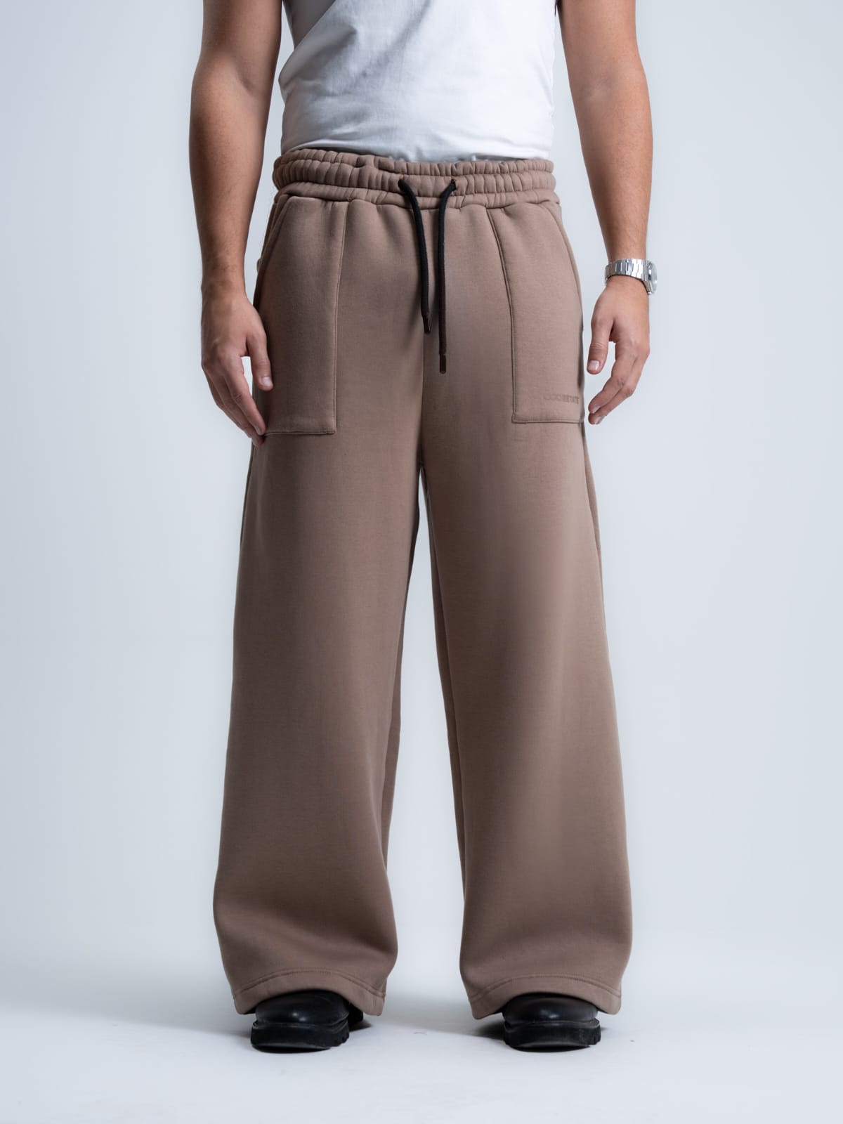 Person wearing brown wide-leg pants on a plain background