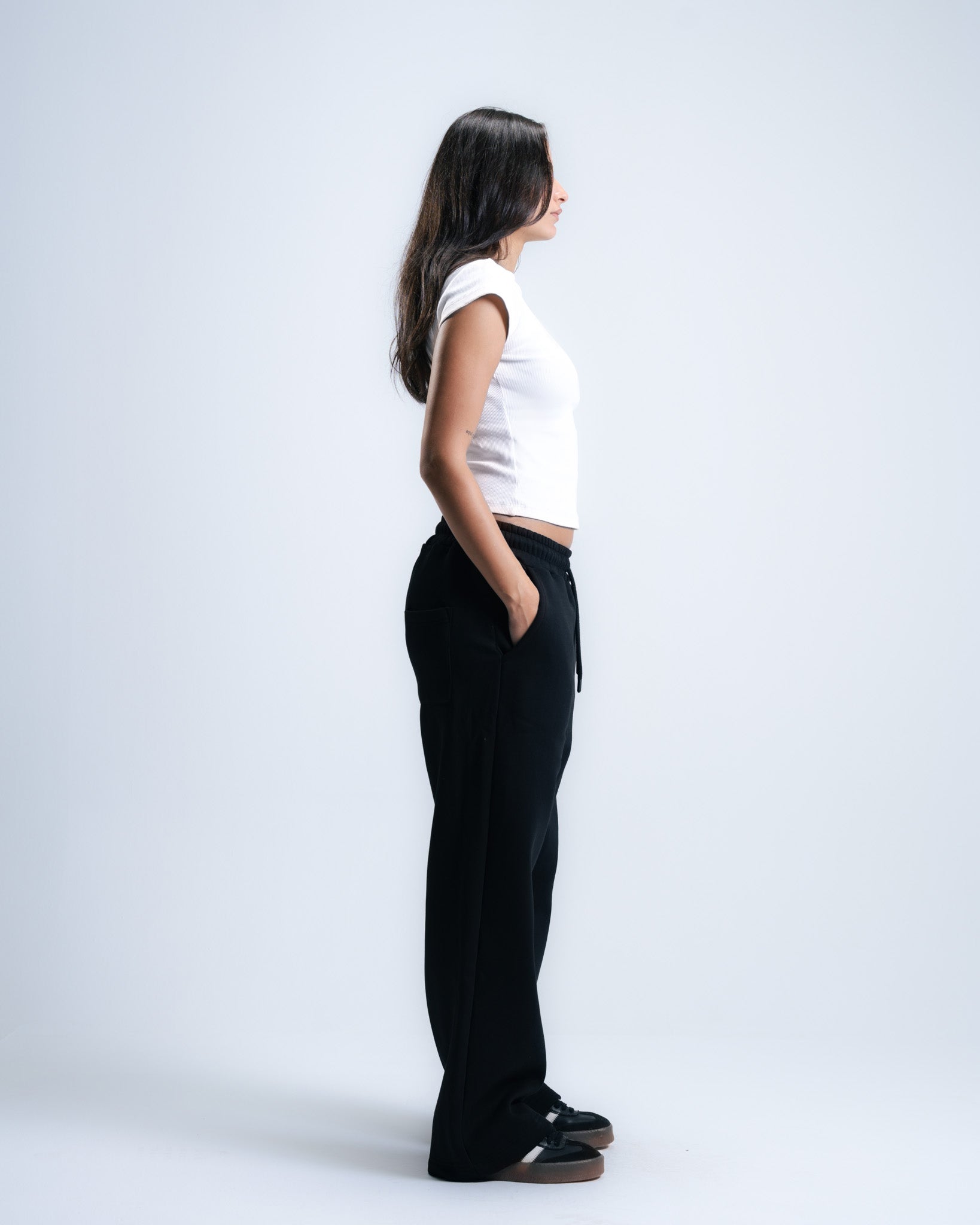 Person wearing a white top and black pants on a white background