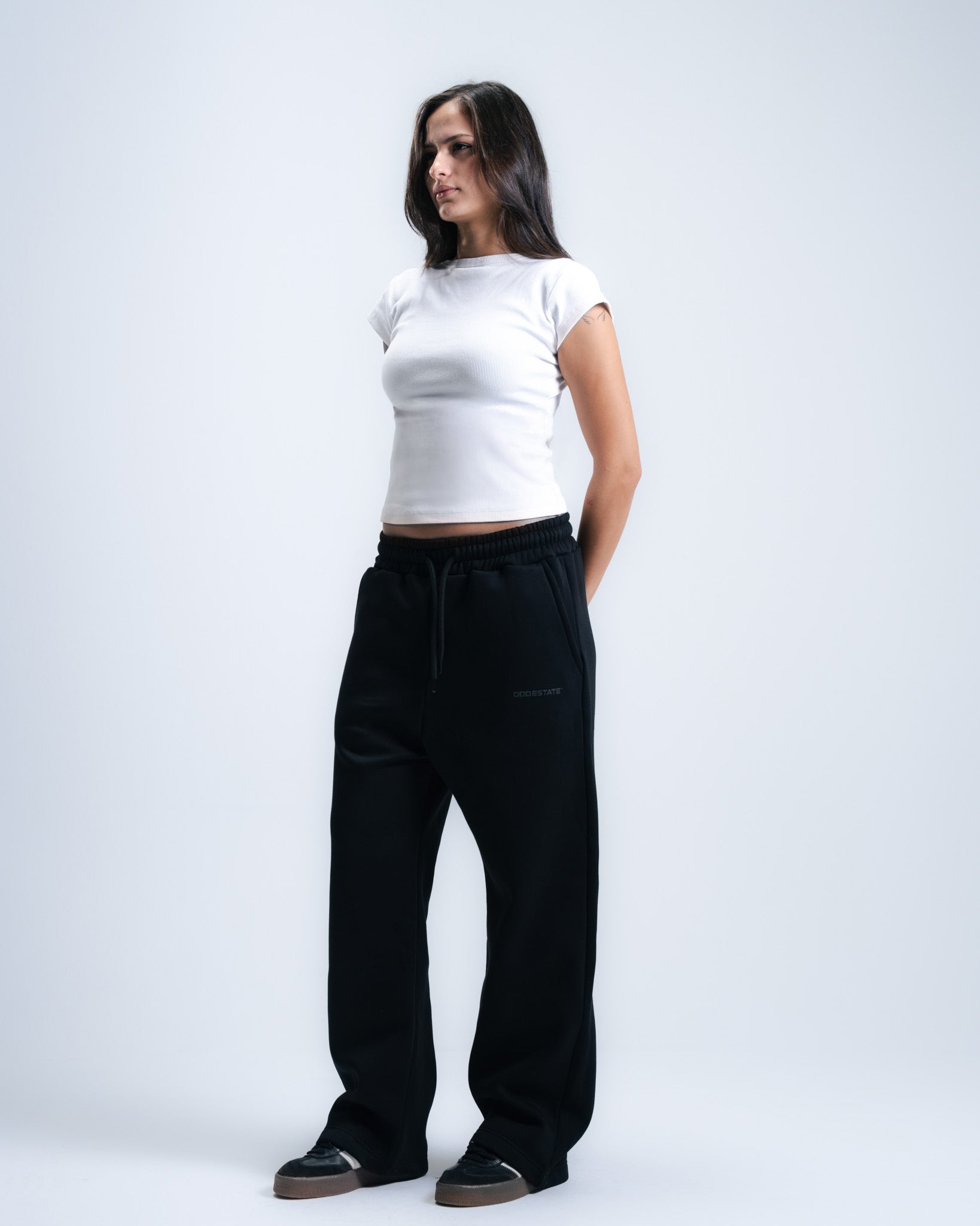 Woman wearing a white top and black pants on a plain background