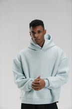 Person wearing a light blue hoodie against a plain background