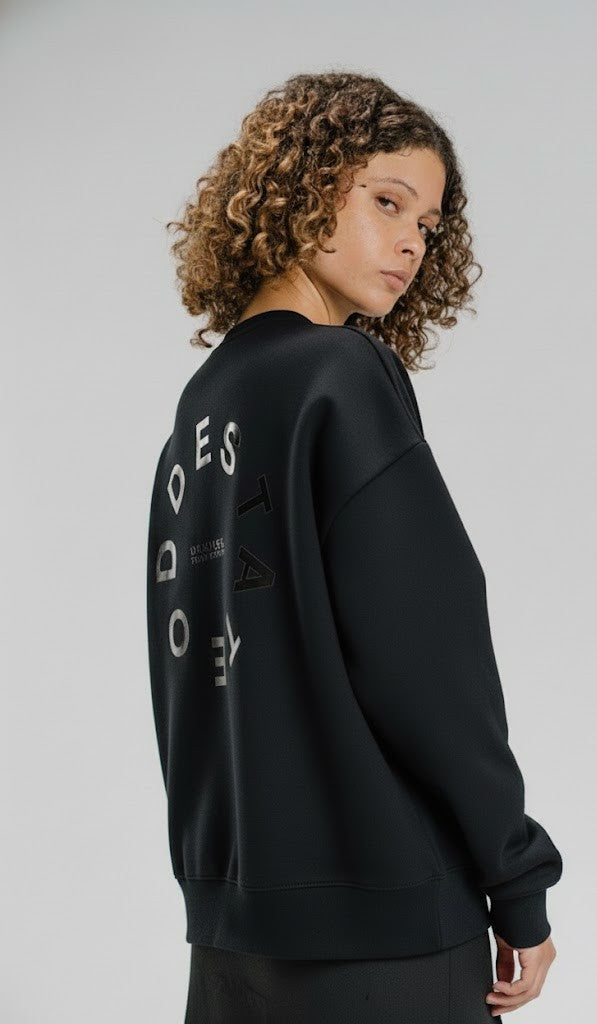 Person wearing a black sweatshirt with text on the back against a plain background