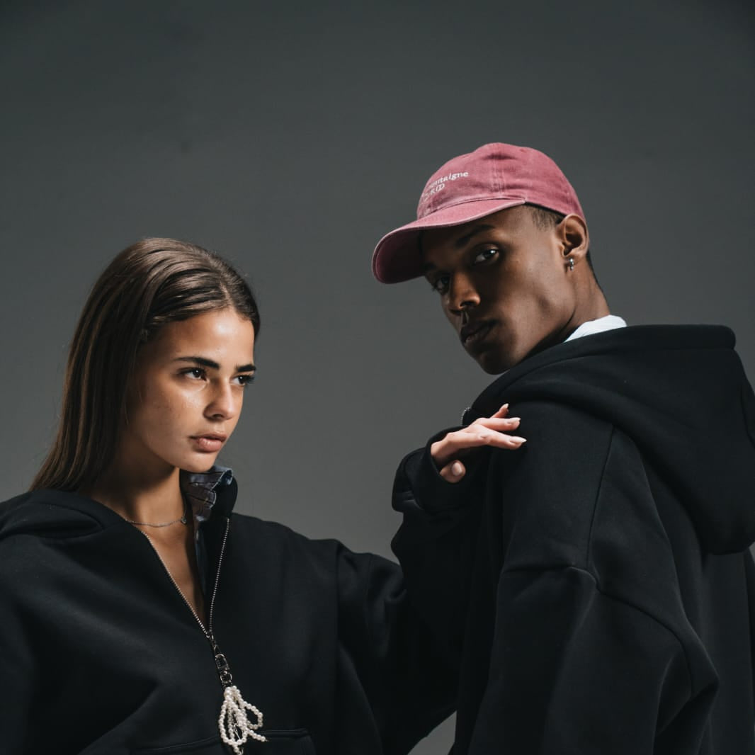 Two people in dark clothing against a gray background